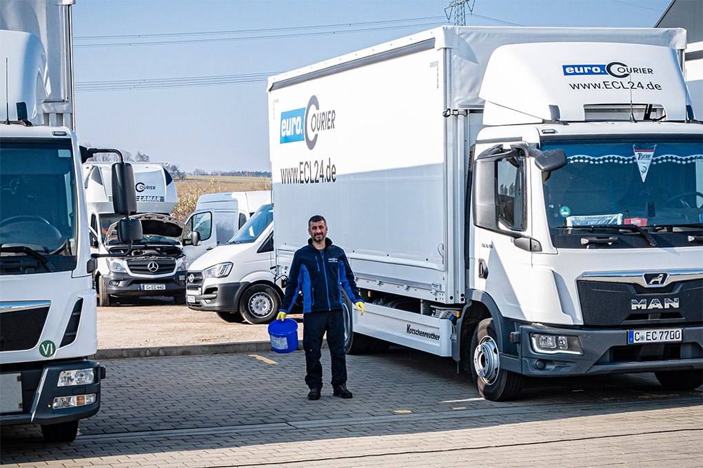 Mitarbeiter mit Wischeimer vor seinem LKW mit dem Logo von euro.COURIER.