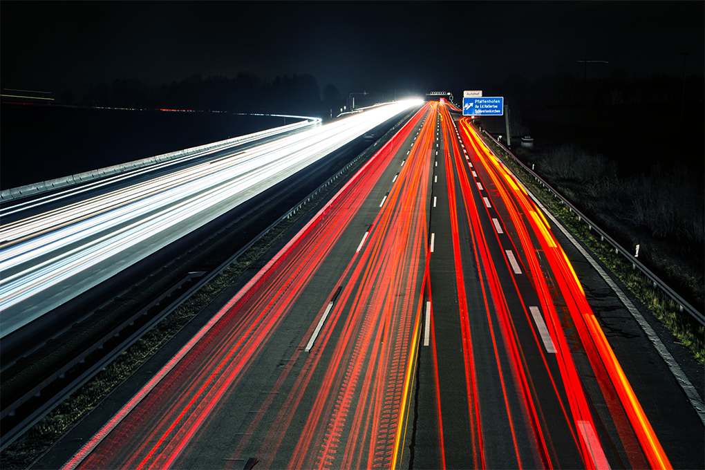 Nachtaufnahme auf der Autobahn mit den Streiflichtern der Fahrzeugkolonnen.