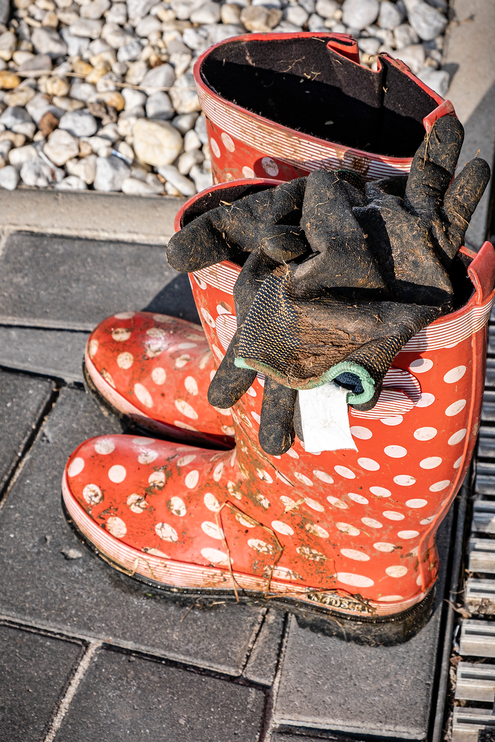 Rote Gummistiefel voll Matsch und dreckige Arbeitshandschuhe zeugen von einem harten Arbeitstag beim Subbotnik von euro.COURIER.