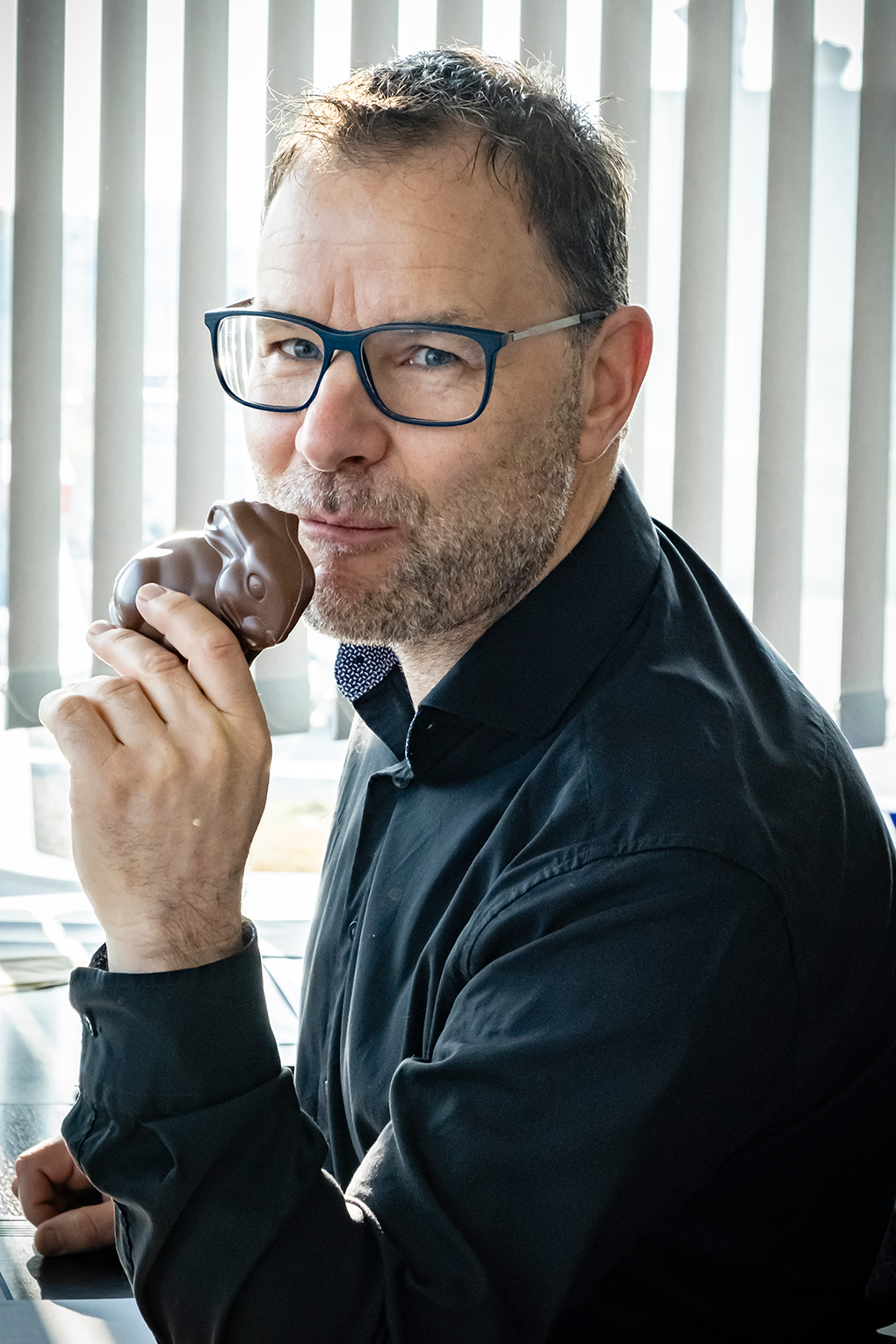 Mitarbeiter nascht den Schokoladenosterhase an seinem Schreibtisch im Büro von der Sonderfahrtenspedition.