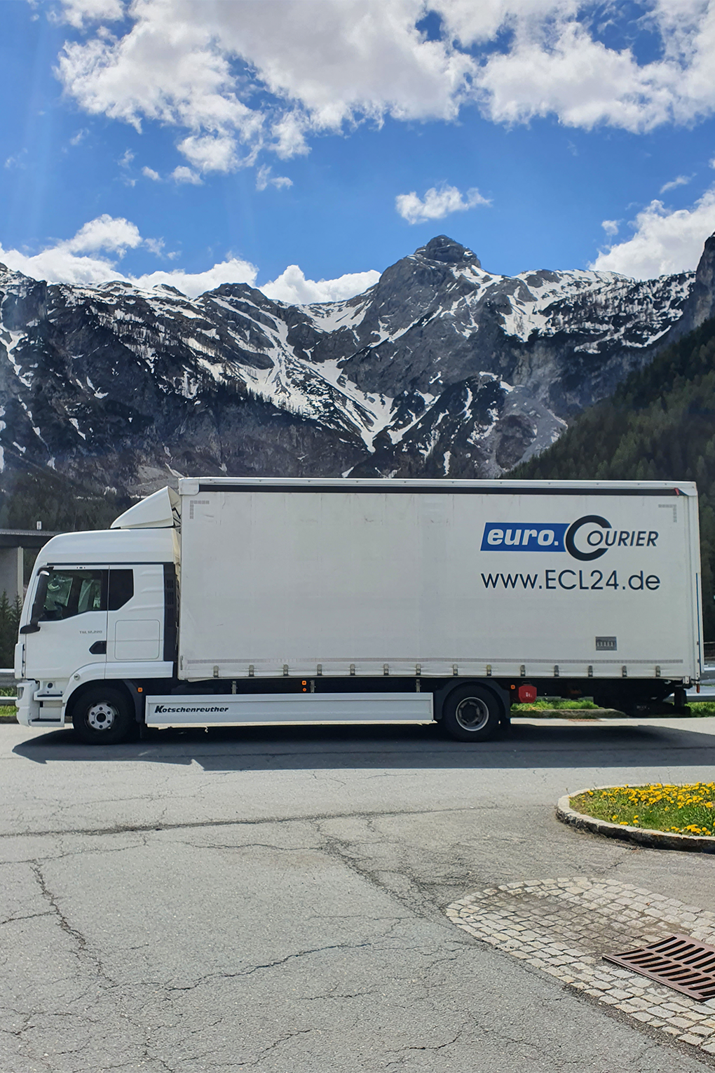 Schicker 12t-LKW für Sonderfahrten vor der berauschenden Kulisse der Alpen mit Schnee bedeckt und Sonnenschein.